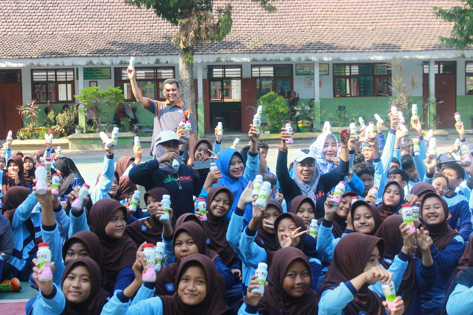 Foto: Kebahagiaan Wiwin Sumrambah, S.Pt. Ketua Umum KORMI Jombang bersama keceriaan siswa SMPN 1 Jombang saat minum susu bersama KORMI Jombang.